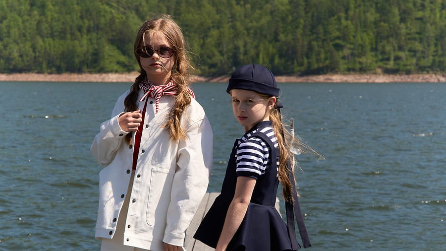 Two girls on a wooden dock, mountain lake backdrop